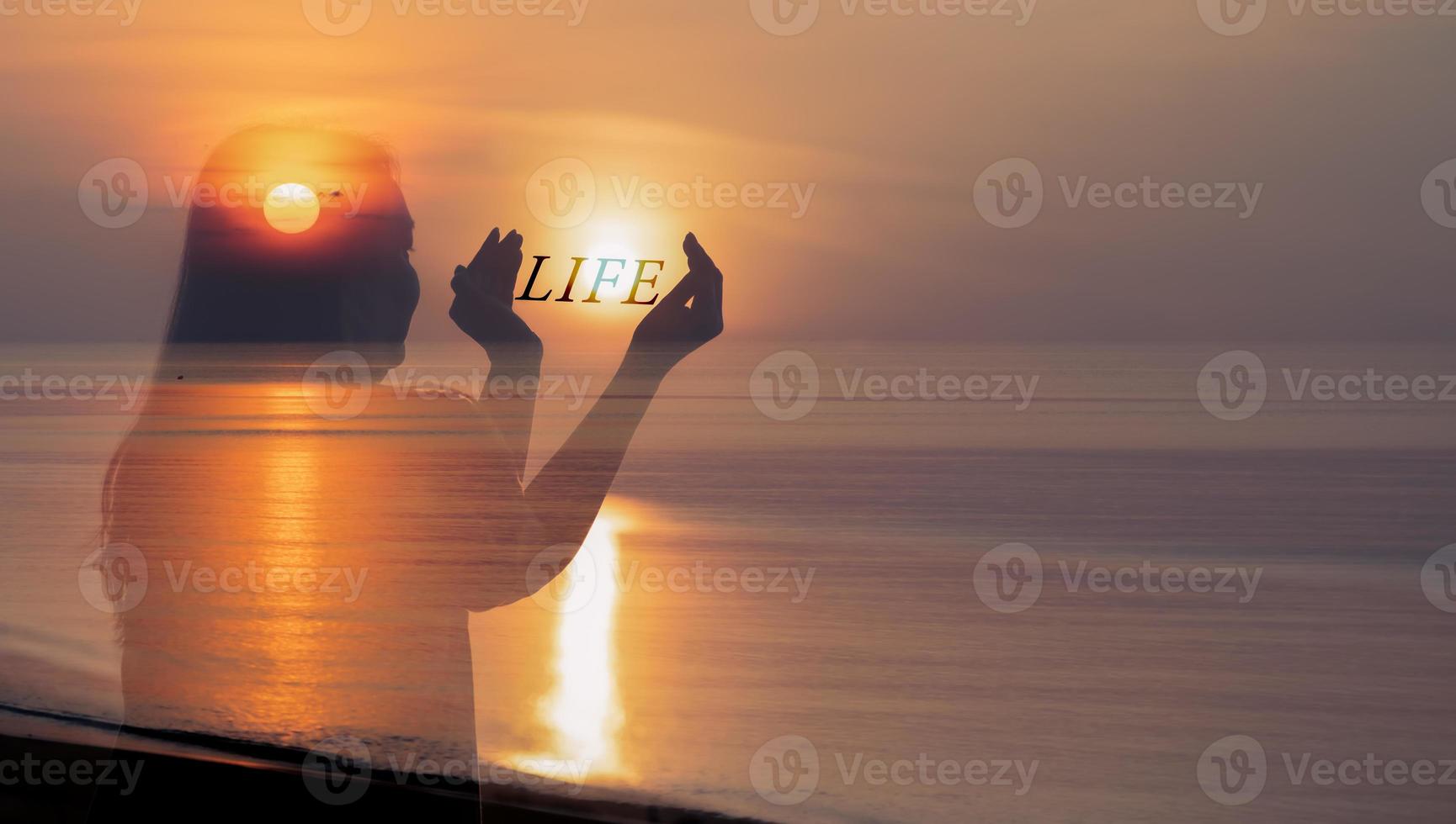 concepto de equilibrio de vida saludable humana, mujer sosteniendo el sol en las manos con texto de carácter de vida al amanecer en la playa. foto