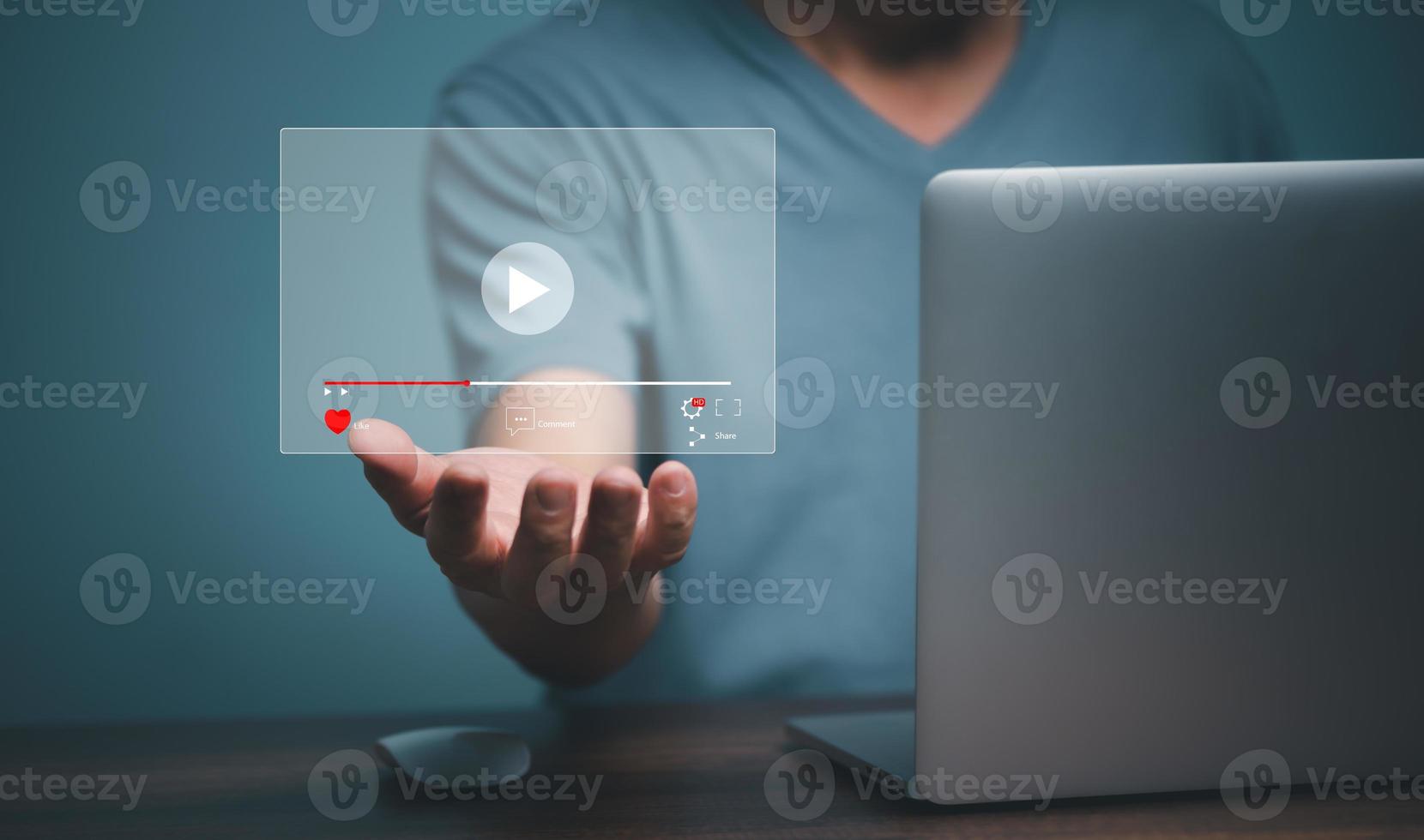 Young man using laptop computer with hand holding virtual playing video streaming screen icon, future screen technology concept. photo