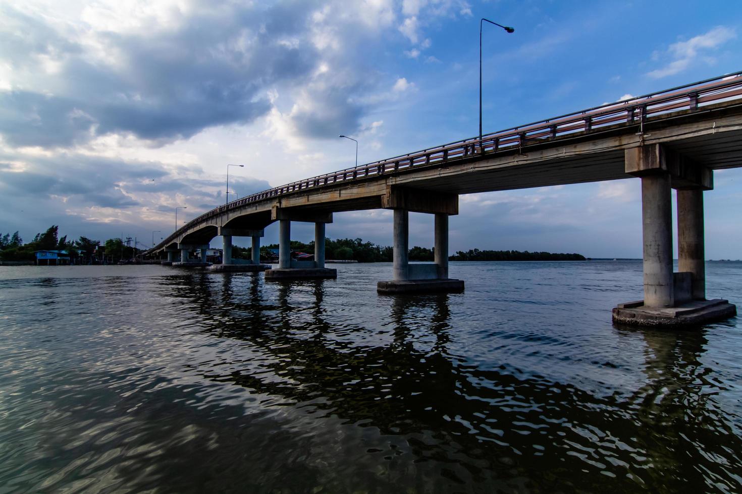 The image of beautiful rain clouds gathered in motion over the bridge over the river photo