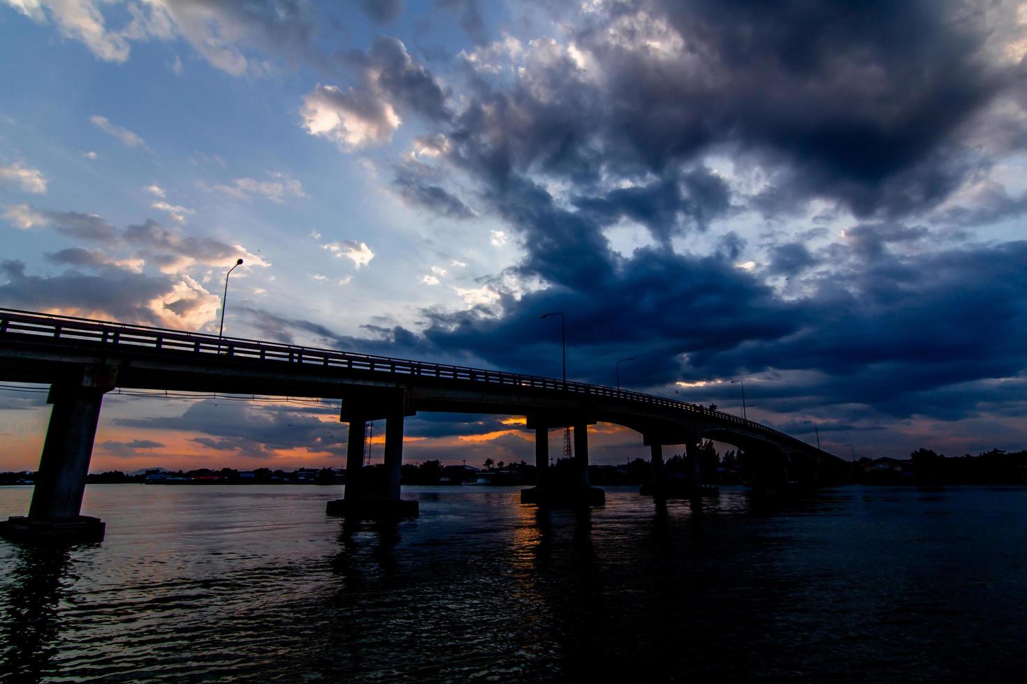 The image of beautiful rain clouds gathered in motion over the bridge over the river photo