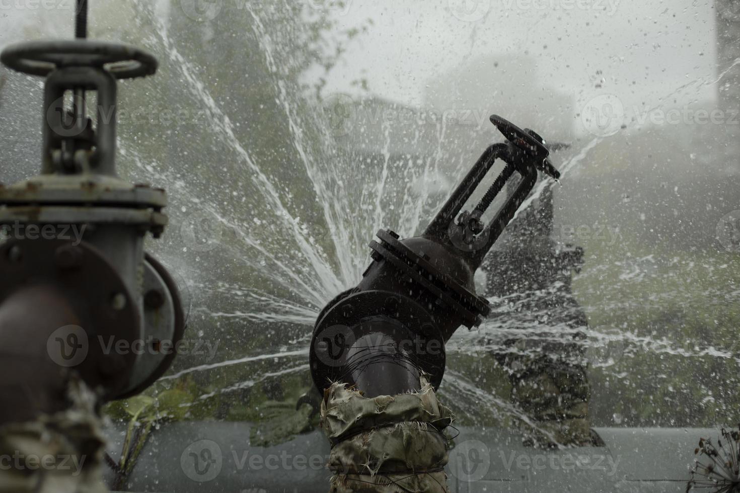 Valve on tube. Torn pipe valve. Boiling water pours from pipeline. photo