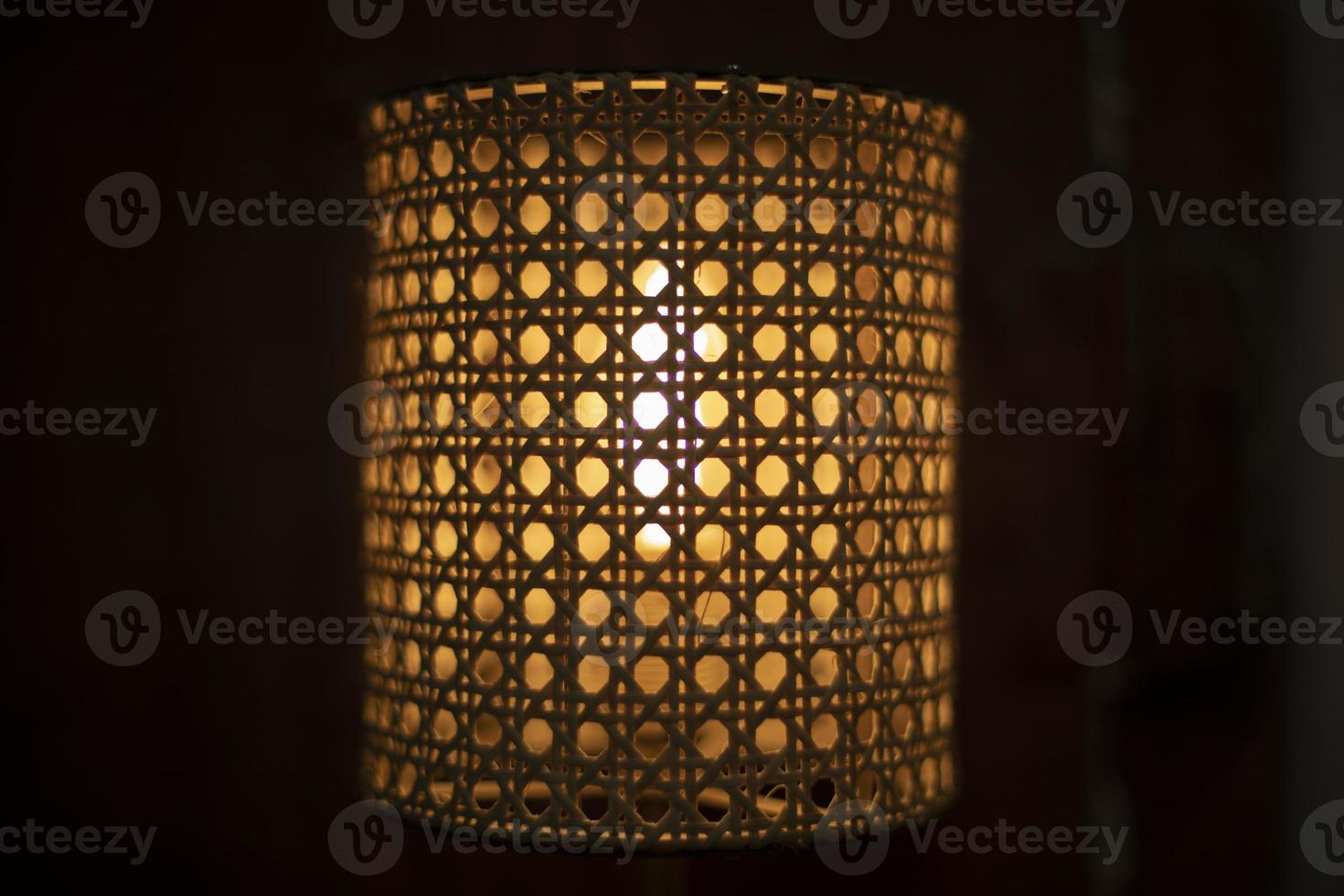 Lamp in dark. Wooden lampshade around incandescent lamp. photo