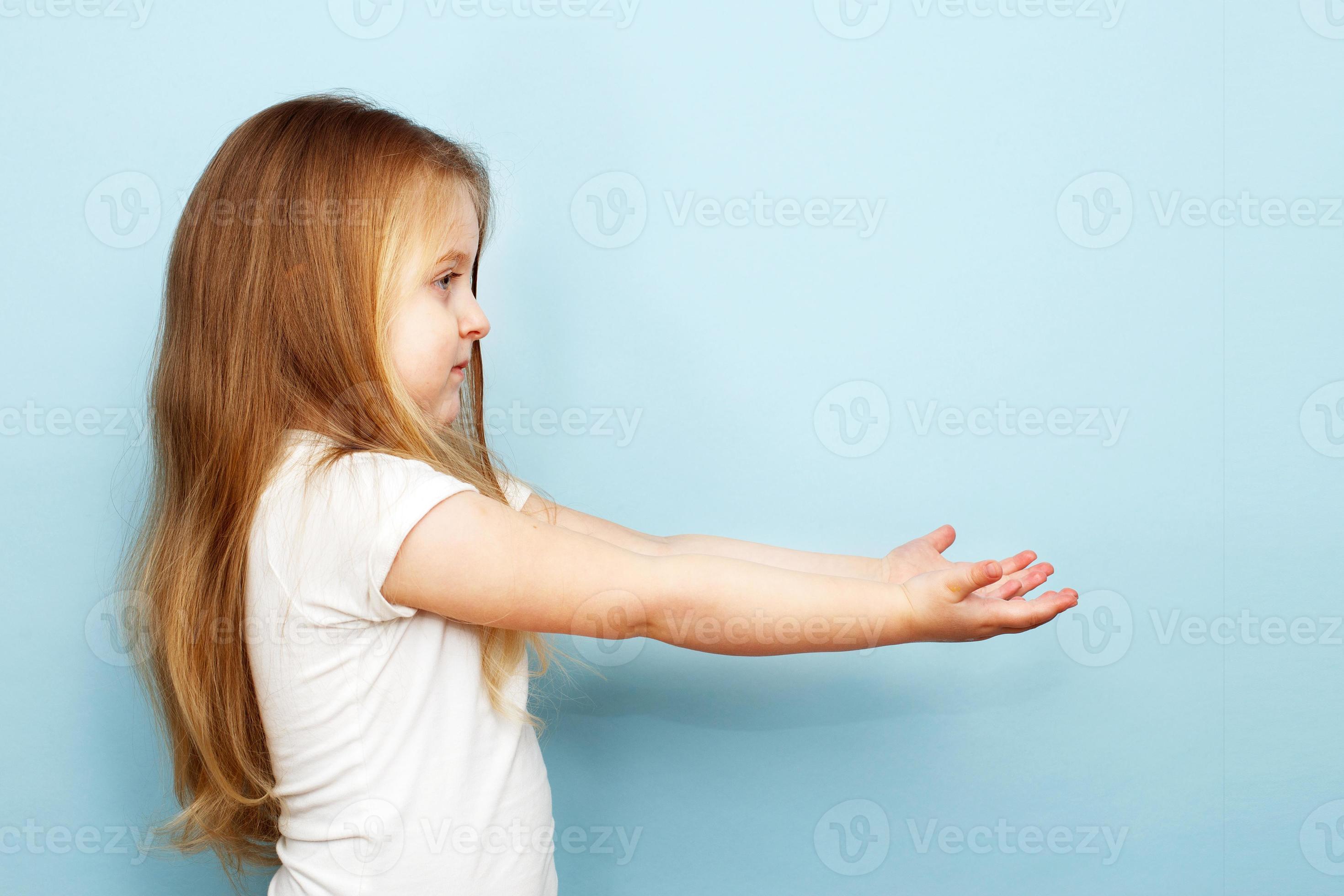 little blonde girl with long hair stretched her arms to the side. child  holding open palm empty hand on blue background 13933298 Stock Photo at  Vecteezy