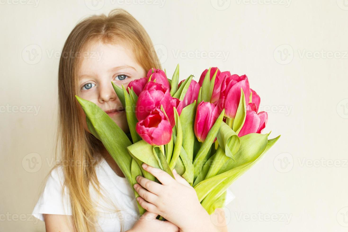 portrait of litlle girl with bouquet of flowers tulips in her hands photo