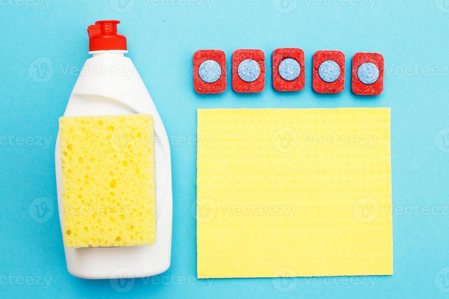 capsules for dishwashers, dishwashing detergents liquid, kitchen rag and sponges on a blue background. photo