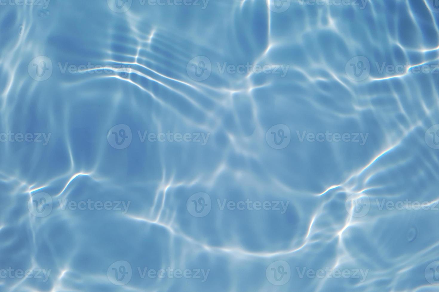 Defocus blurred transparent blue colored clear calm water surface texture with splashes and bubbles. Trendy abstract nature background. Water waves in sunlight with copy space. Blue watercolor shining photo
