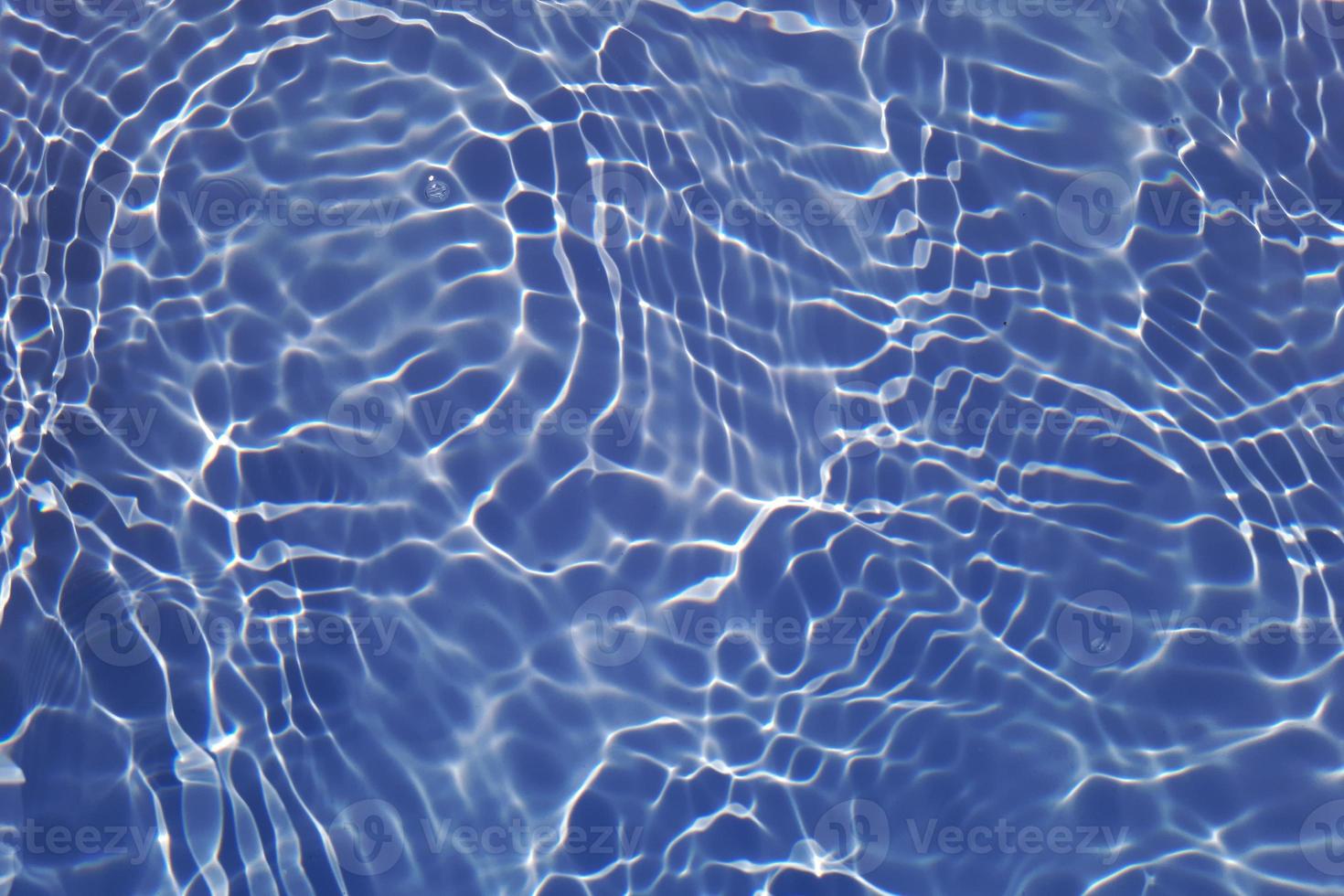 Defocus blurred transparent blue colored clear calm water surface texture with splashes and bubbles. Trendy abstract nature background. Water waves in sunlight with copy space. Blue watercolor shining photo