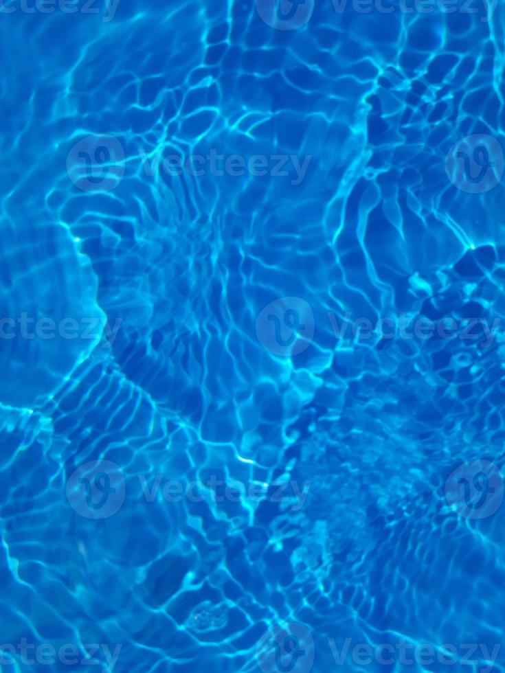 Defocus blurred transparent blue colored clear calm water surface texture with splashes and bubbles. Trendy abstract nature background. Water waves in sunlight with copy space. Blue watercolor shining photo