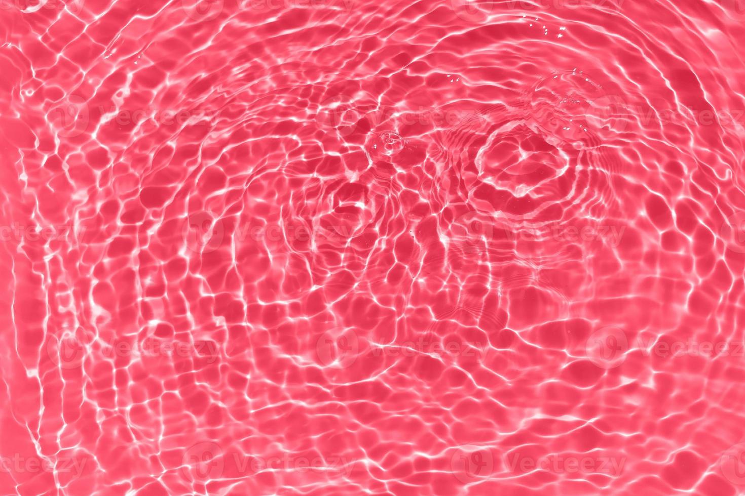 Defocus blurred transparent red colored clear calm water surface texture with splashes and bubbles. Trendy abstract nature background. Water waves in sunlight with copy space. Red watercolor shining photo