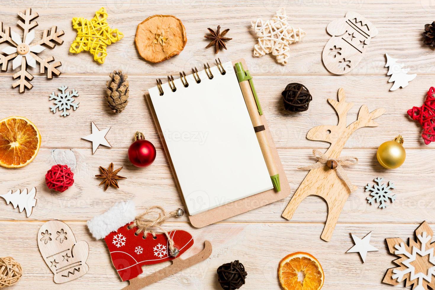 Top view of notebook on wooden background made of Christmas decorations. New Year concept photo