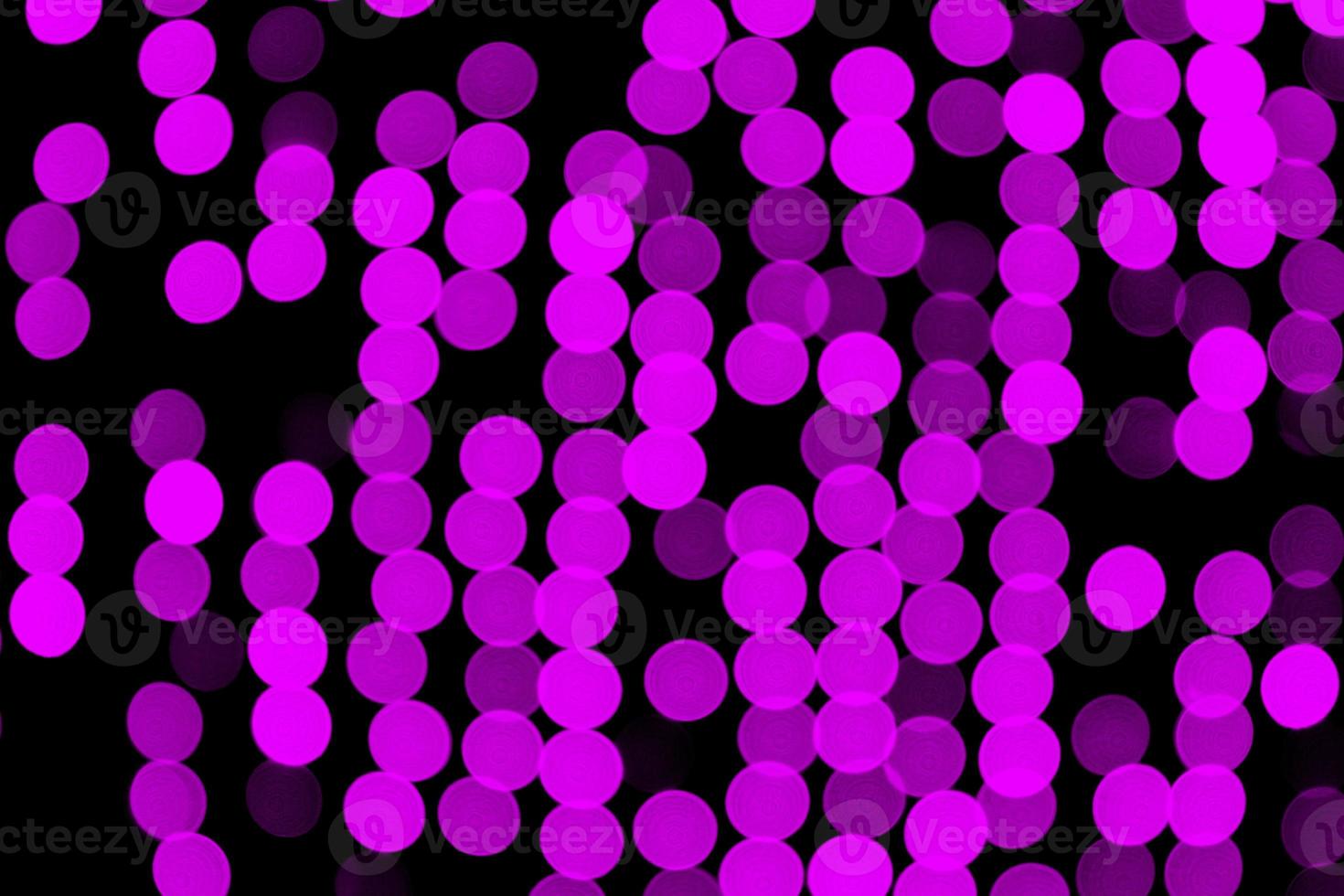 Unfocused abstract purple bokeh on black background. defocused and blurred many round light photo