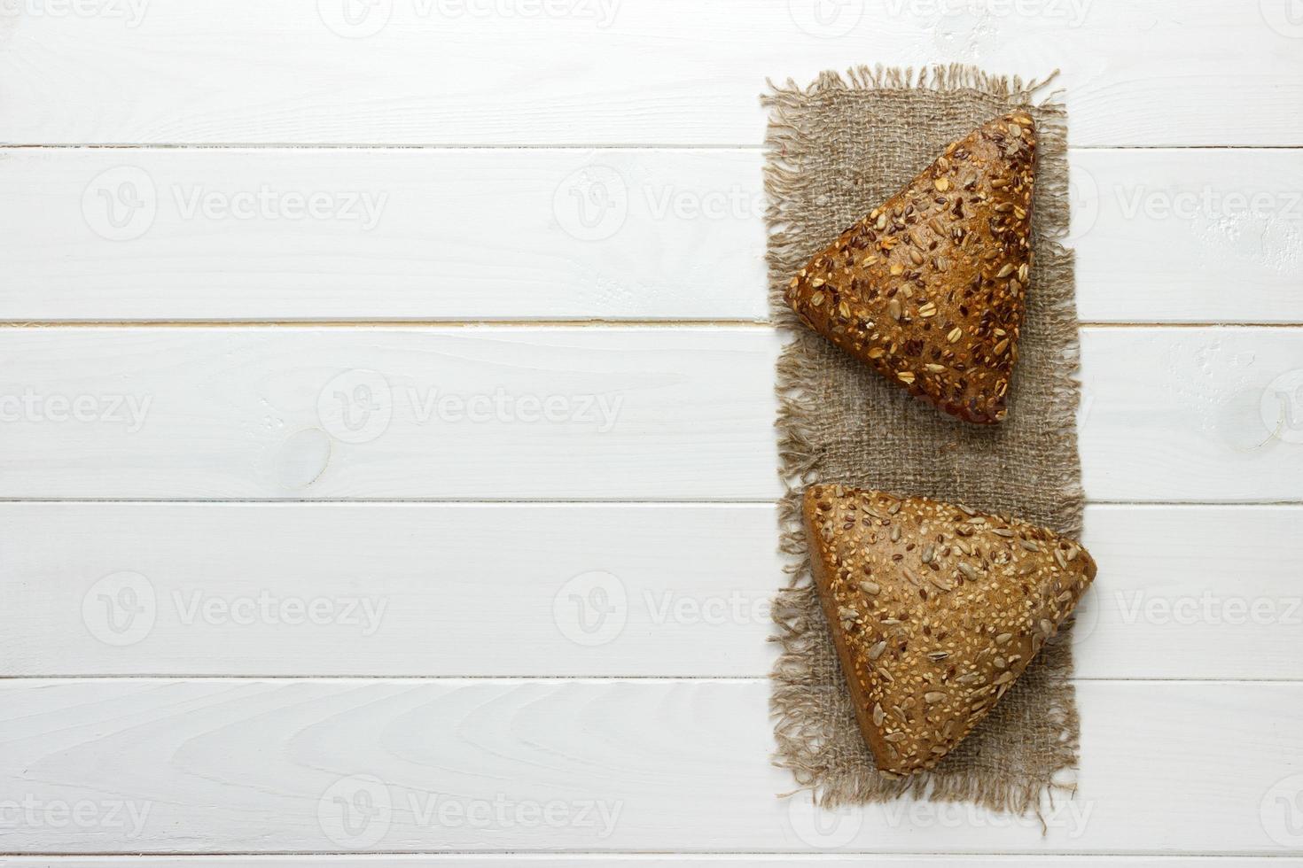 Several small multi grain triangular shaped bread sprinkled with whole sunflower seeds, flax and sesame seeds on a sackcloth photo