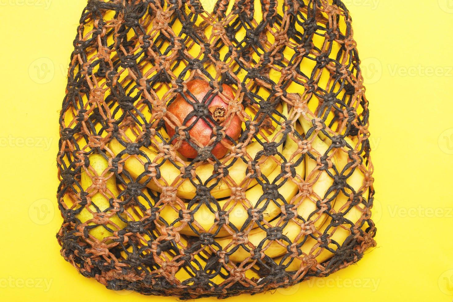 brown string bag with ripe fruits on a yellow background photo