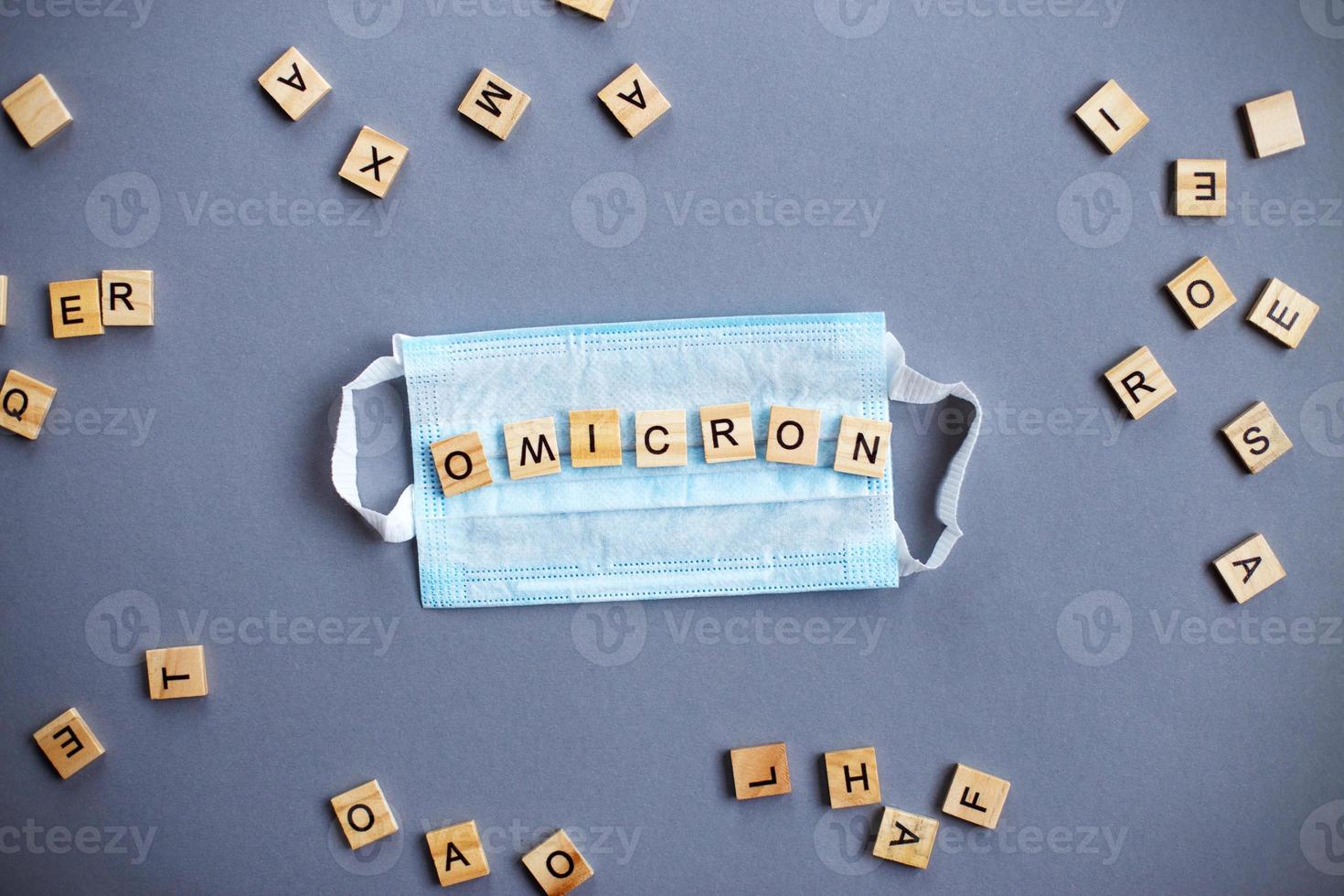 word omicron made by wooden blocks with medical mask on gray background. photo