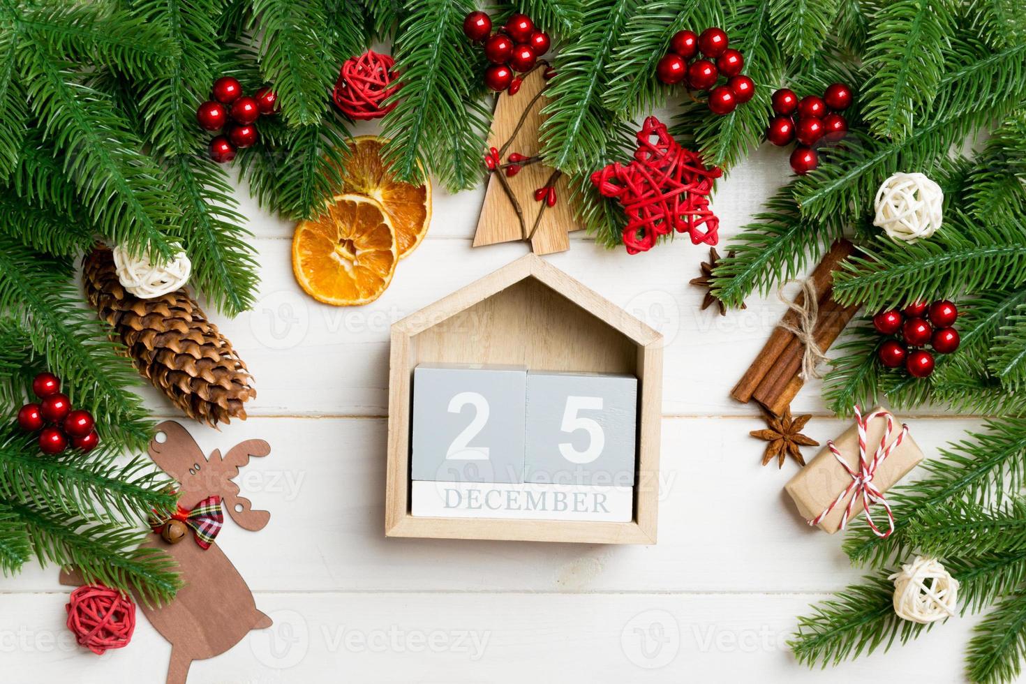 Top view of fir tree branches on wooden background. Calendar decorated with festive toys. The twenty fifth of December. Christmas time concept photo