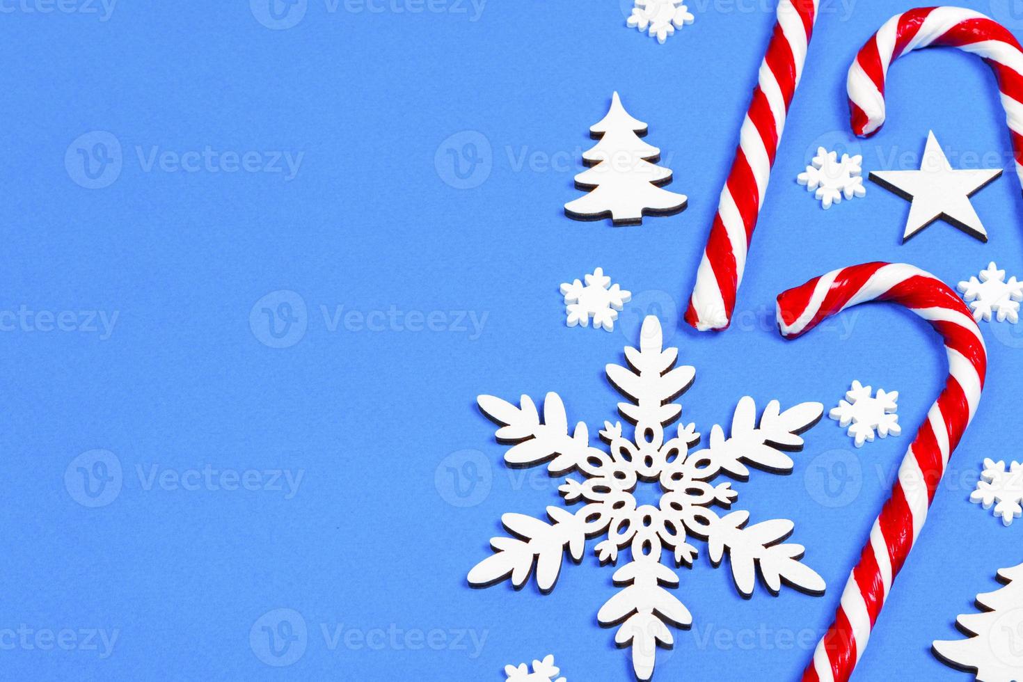 Christmas candy cane lied evenly in row on blue background with decorative snowflake and star. Flat lay and top view photo