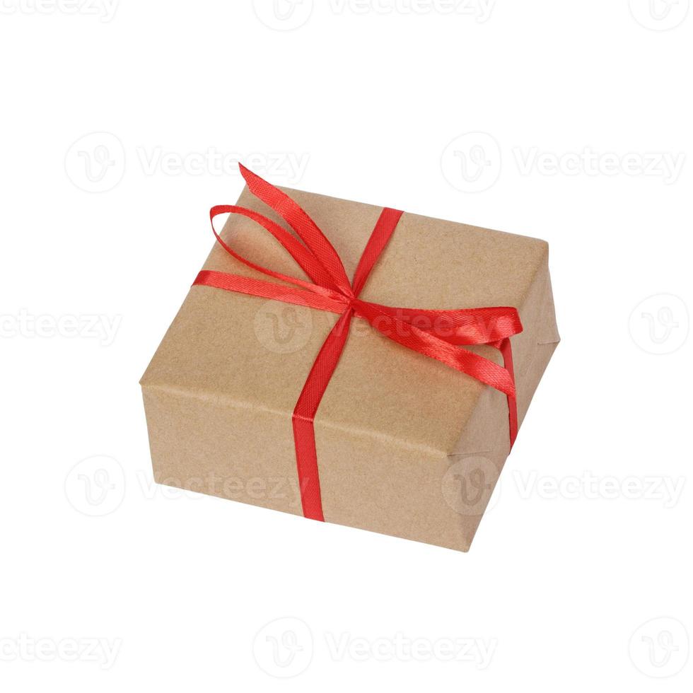 Gift box wrapped in brown recycled paper with red ribbon bow top view isolated on white background, clipping path included photo