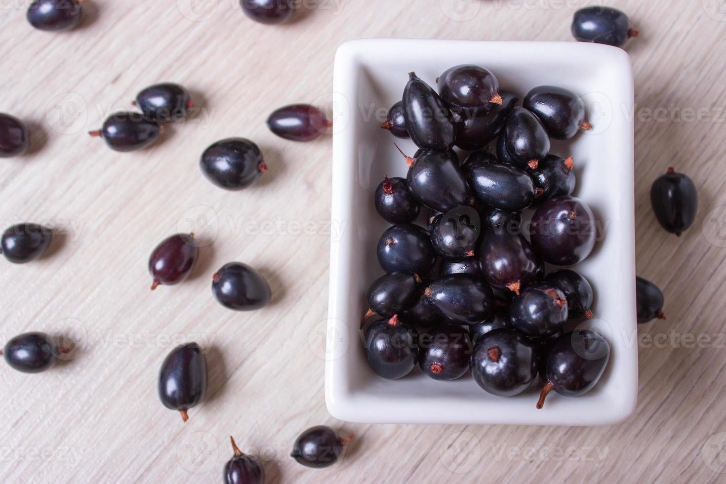 black currant in glassware on white wooden table top view photo