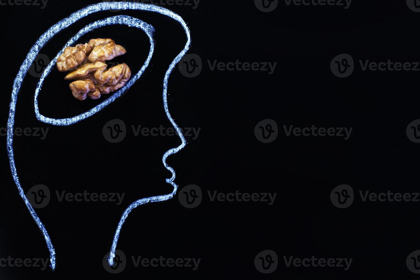 silhouette of person drawn head with abstraction brain in the form of walnut on black background. healthy food to think. photo