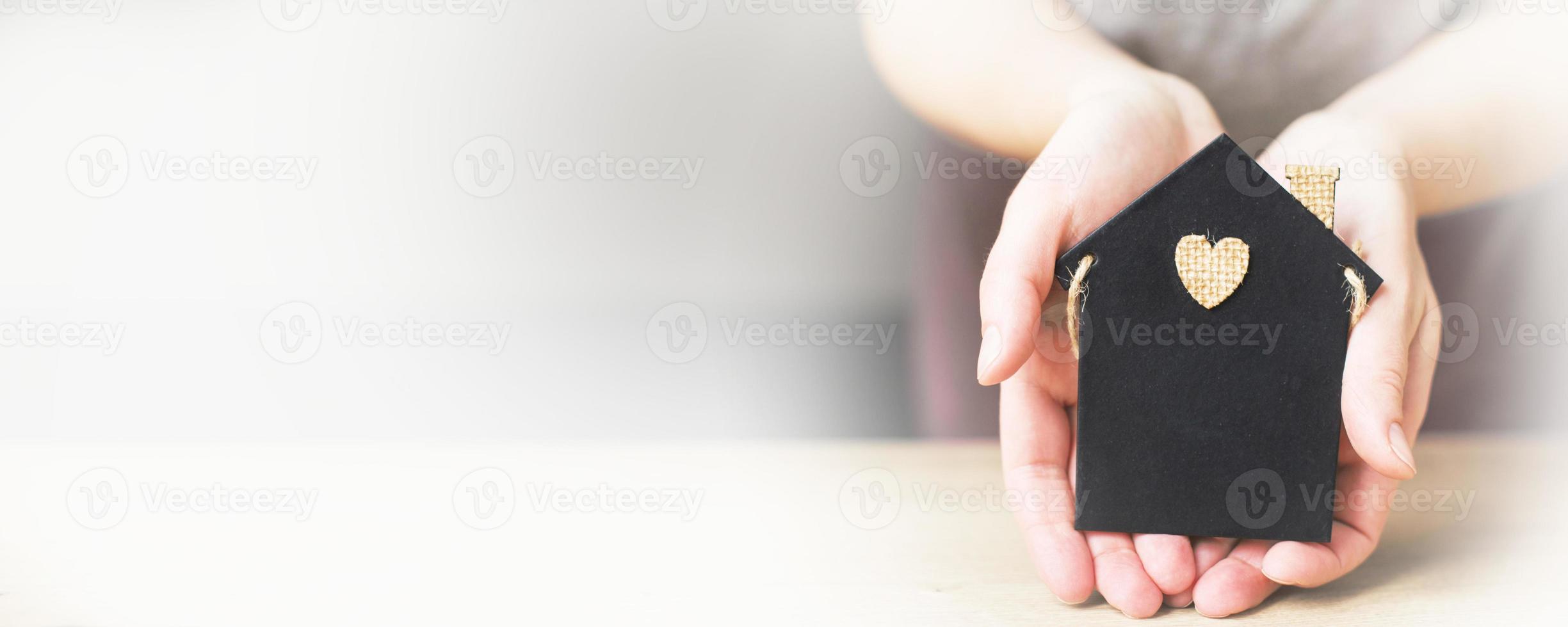 womans hand holding little toy house. Home insurance concept photo