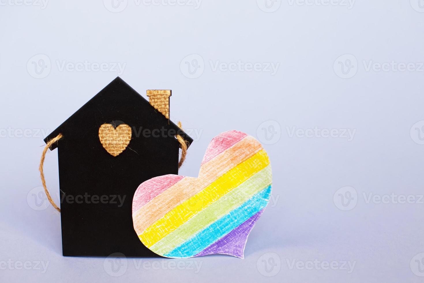 heart in the form of a lgbt flag next to a miniature toy house. photo