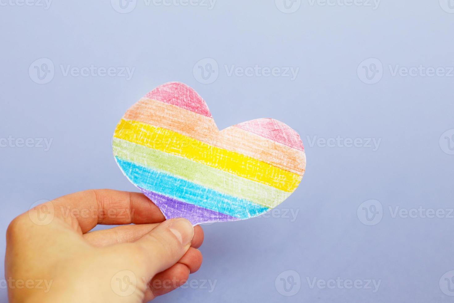 hands holding lgtb flag in the form of a heart on a purple backgroubd photo