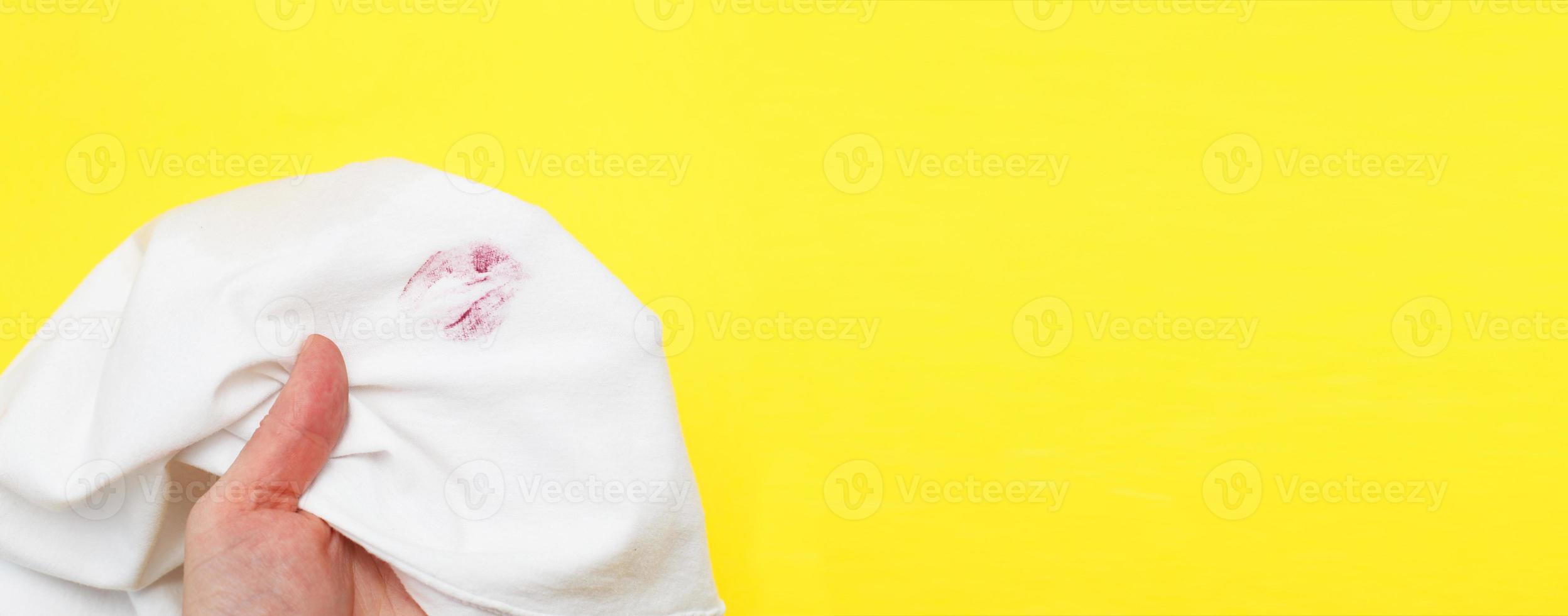 Woman holding a white shirt with red kiss lipstick on a yellow background photo