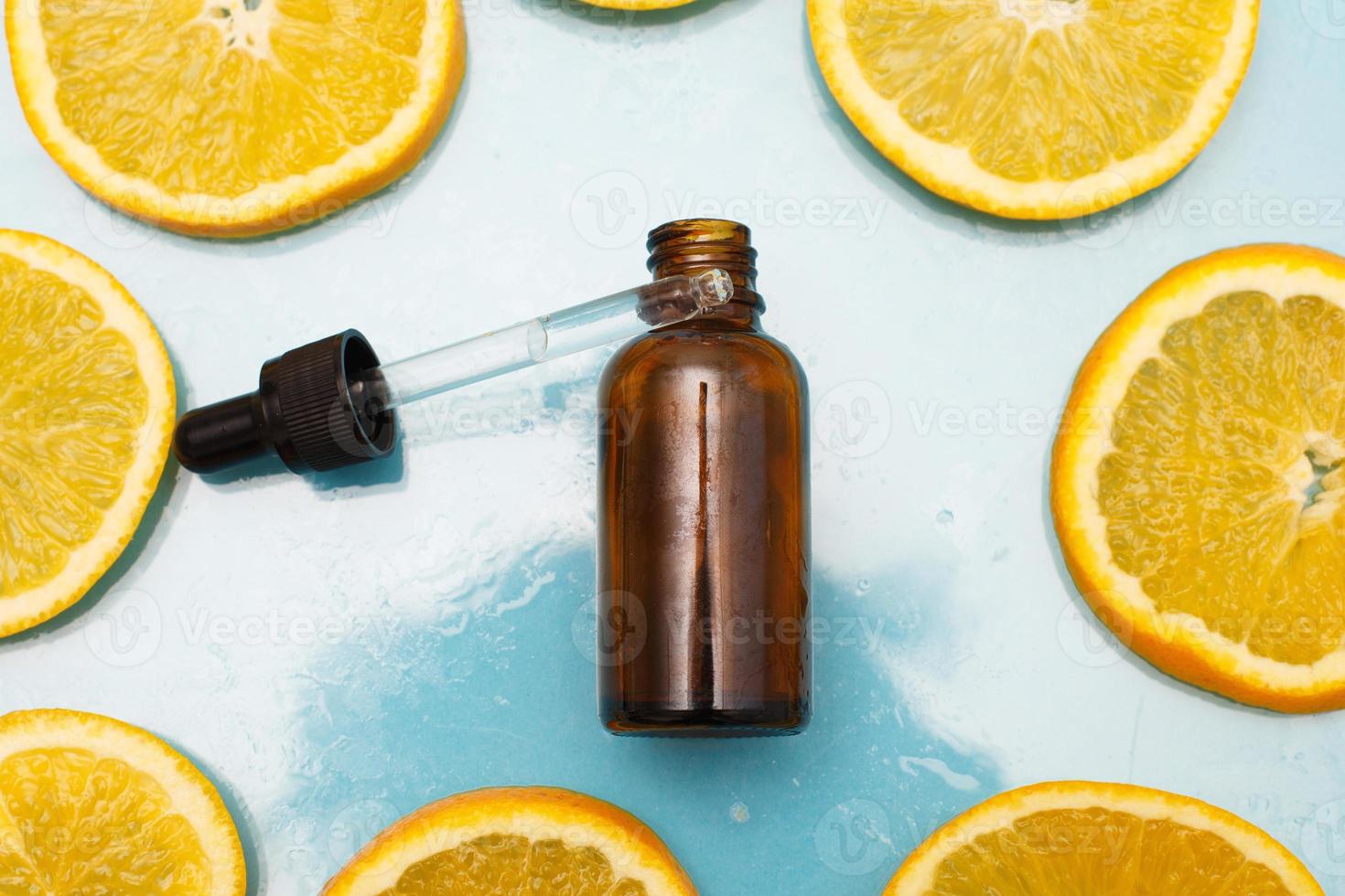 frasco de vidrio marrón con suero de pipeta con vitamina c. aceite esencial y rodajas de naranja. concepto de salud y belleza. foto