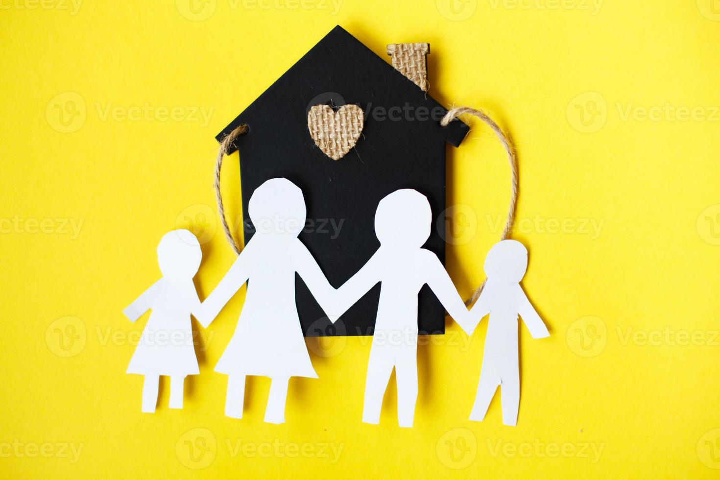 Happy paper cut family holding hands on yellow background near little toy house photo