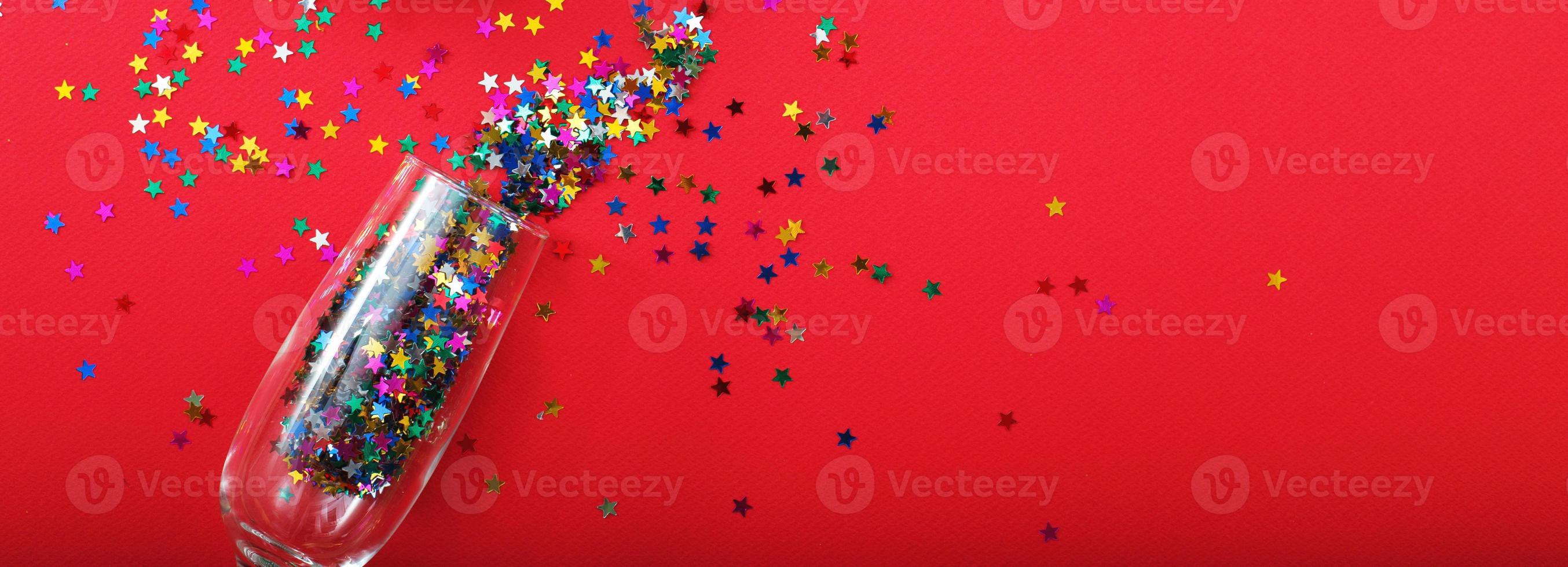 Champagne glass with star shaped sequins on a red background. banner. Party, christmas, new year, concept. photo
