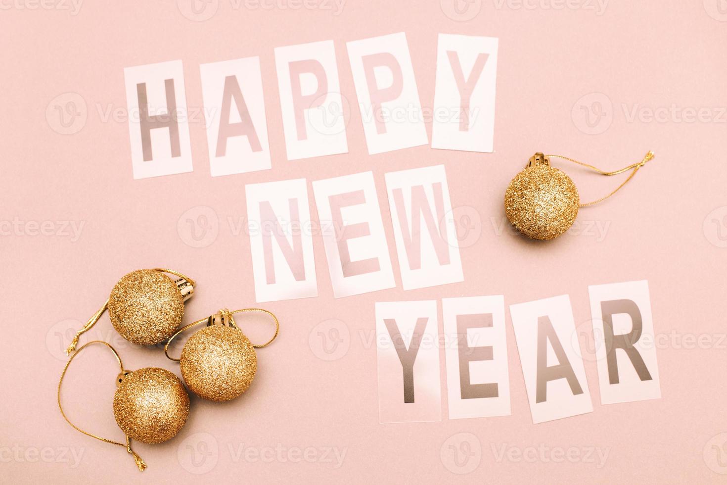 The inscription happy new year with shiny Christmas toy balls on a pink background photo