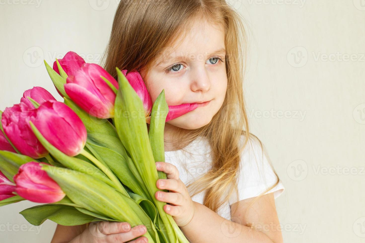 portrait of litlle girl with bouquet of flowers tulips in her hands photo
