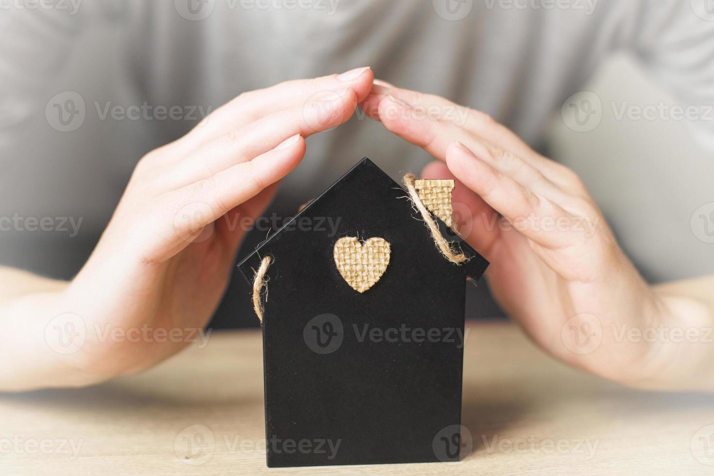 womans hand covered little toy house. Home insurance concept photo