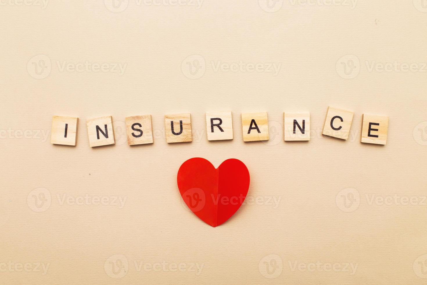 inscription insurance on a beige background made by wooden blocks with red heart photo