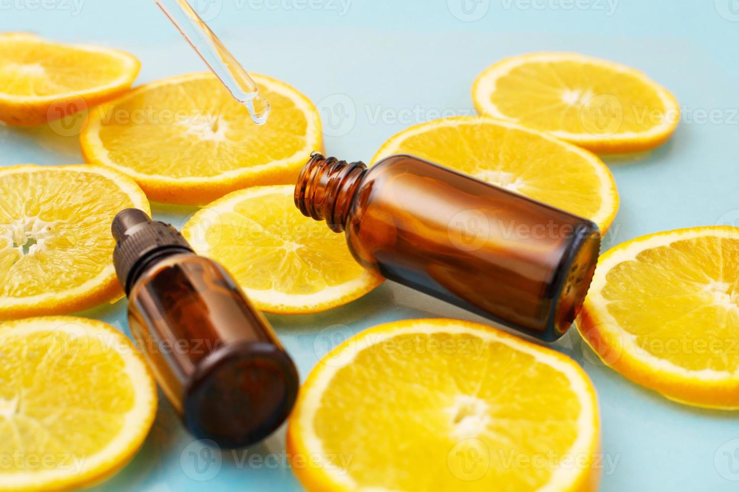 frasco de vidrio marrón con suero de pipeta con vitamina c. aceite esencial y rodajas de naranja. concepto de salud y belleza. foto