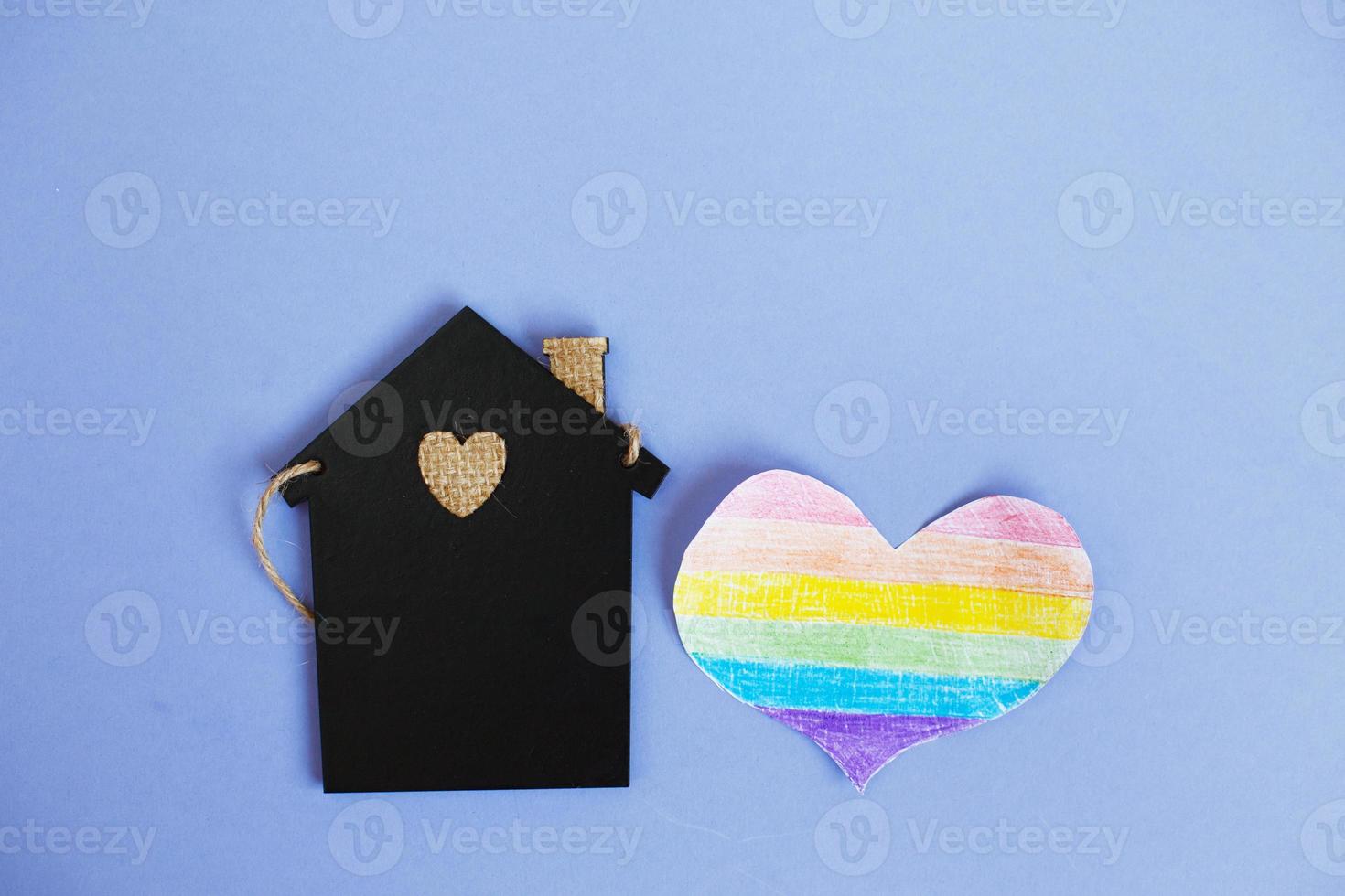 heart in the form of a lgbt flag next to a miniature toy house. photo
