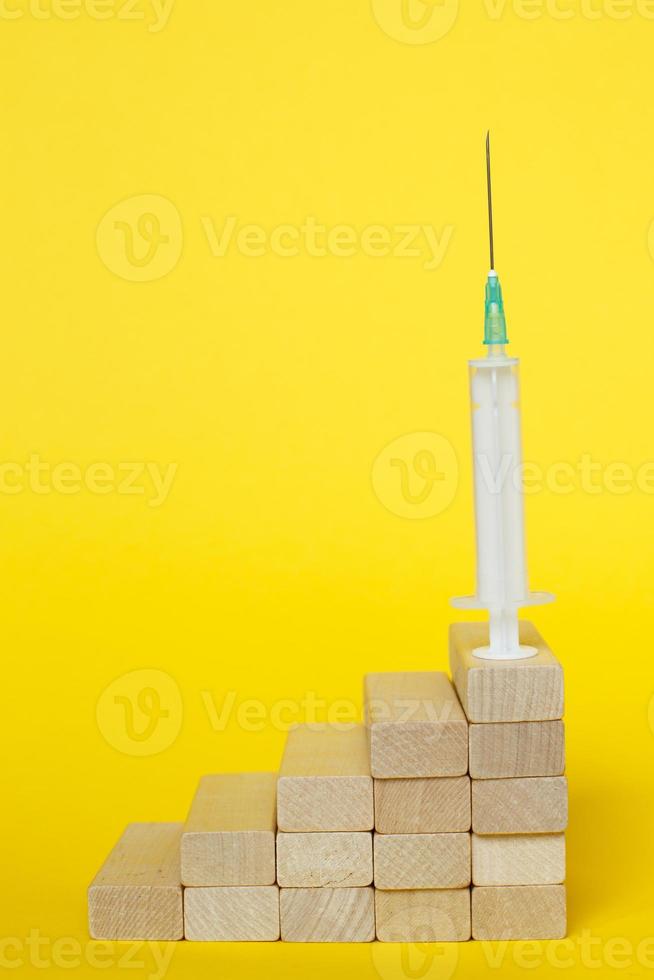 medical syringe on ladder made of wooden sticks. drugs, vaccination concept photo
