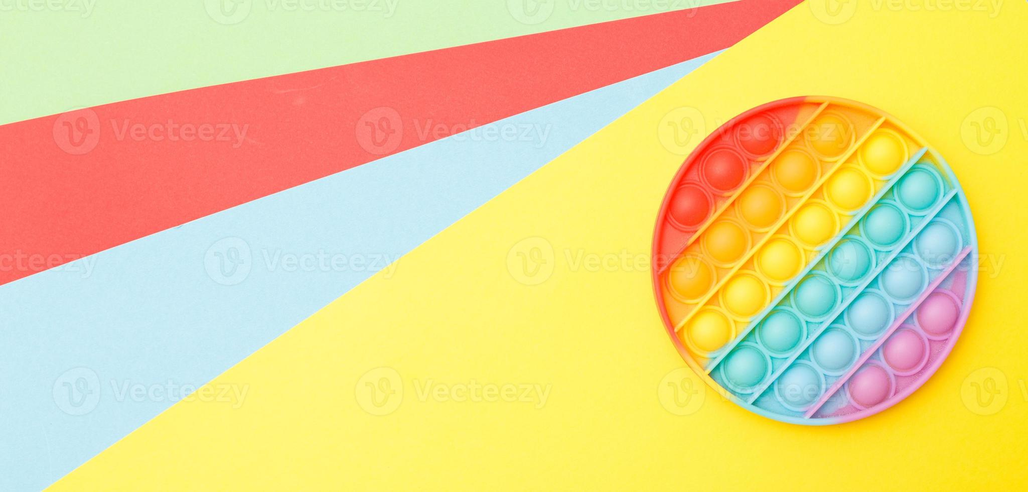 modern trendy silicone toy pop on a multicolored background. children's educational antistress toy photo
