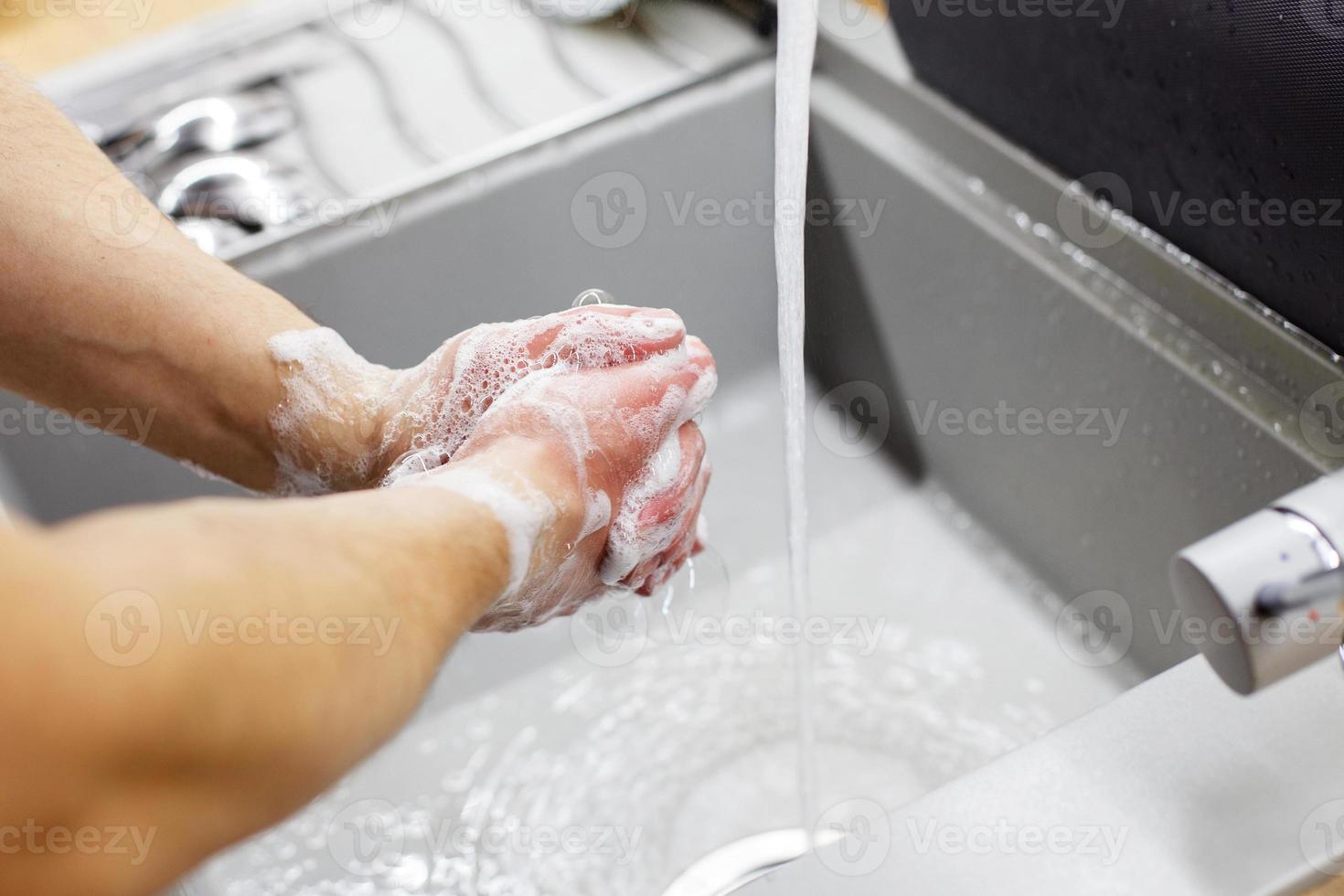 A man washes his hands with soap under the tap under running water close-up. Health, and hygiene concept. photo