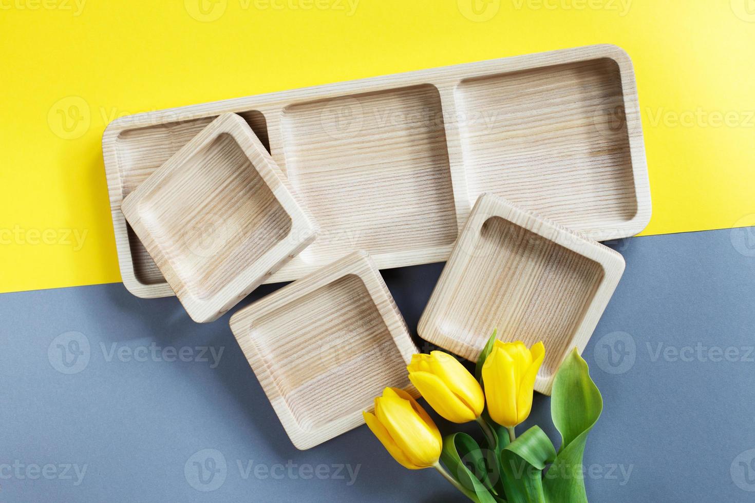 wood empty plates for snack and flowers on color grey and yellow background photo
