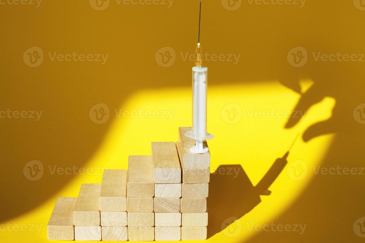 shadow of a man's hand about to steal a syringe with a vaccine on yellow background photo