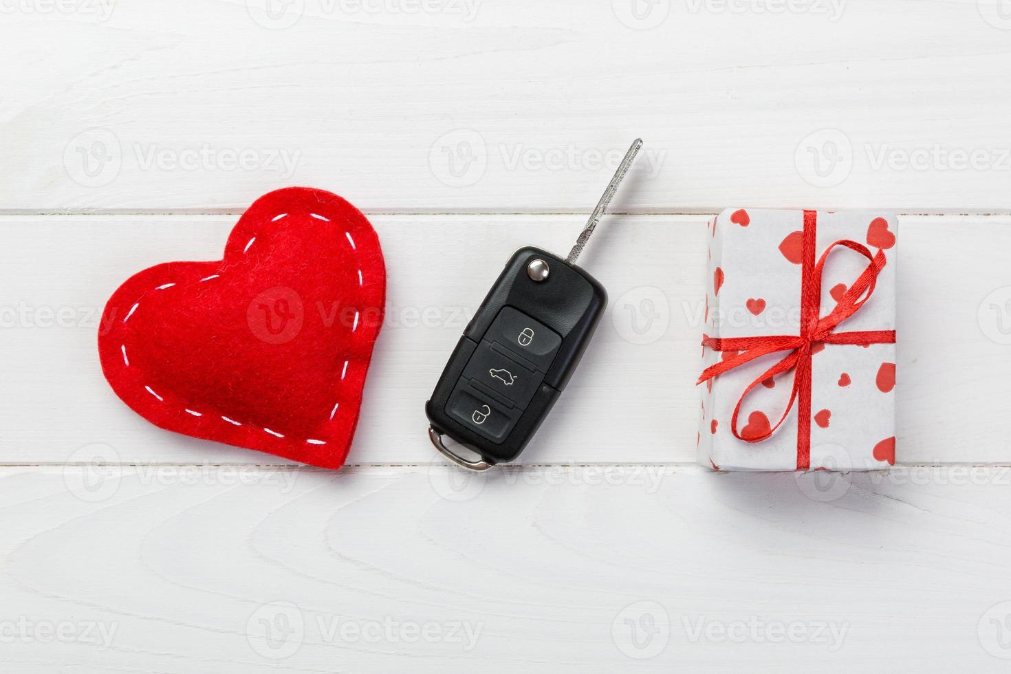 Valentine or other holiday handmade present in paper with red hearts, car keys and gifts box in holiday wrapper. box gift on white wooden table top view with copy space, empty space for design photo