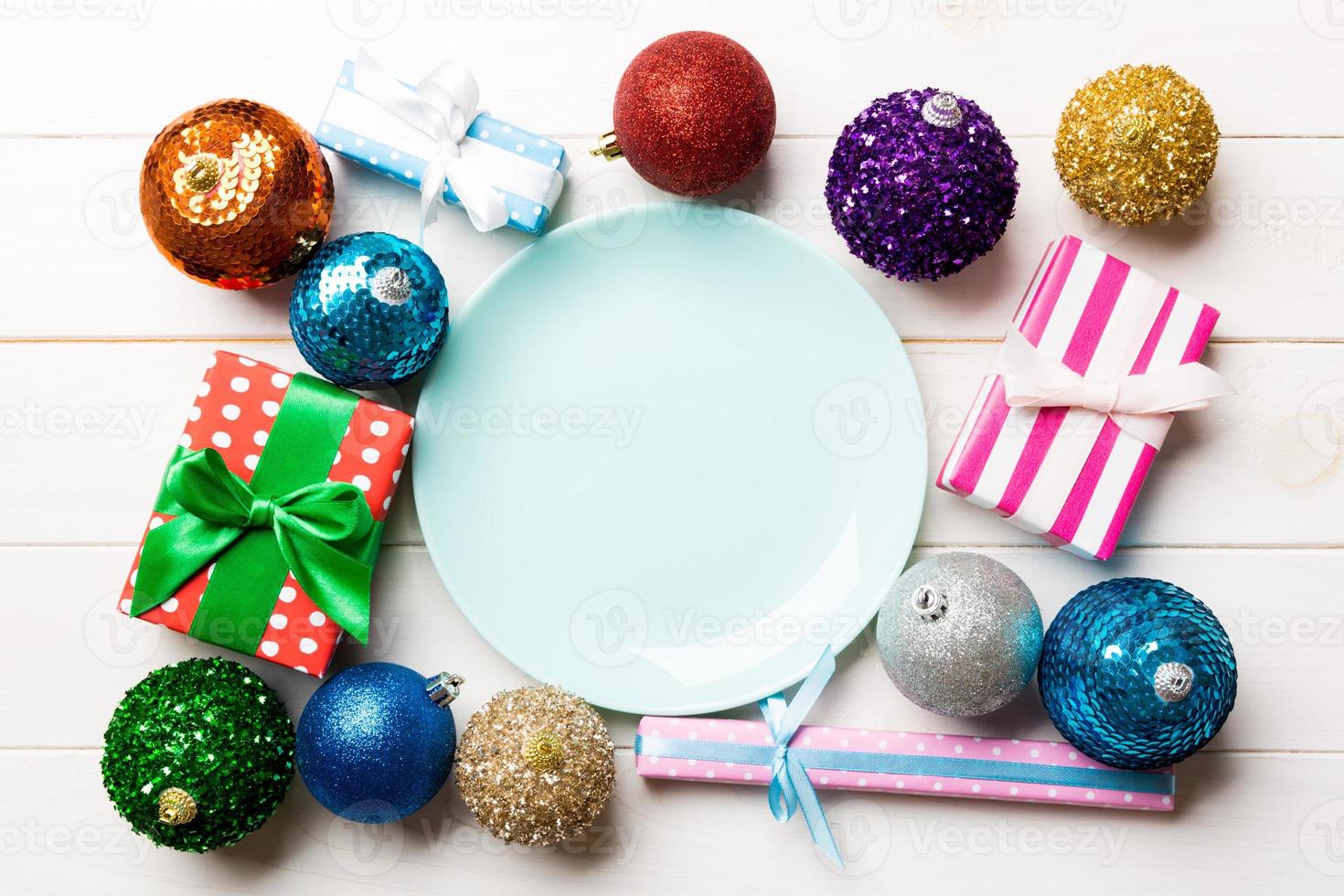Top view of holiday setting on wooden background. Plate, gifts, baubles and Christmas decorations. New Year dinner concept photo