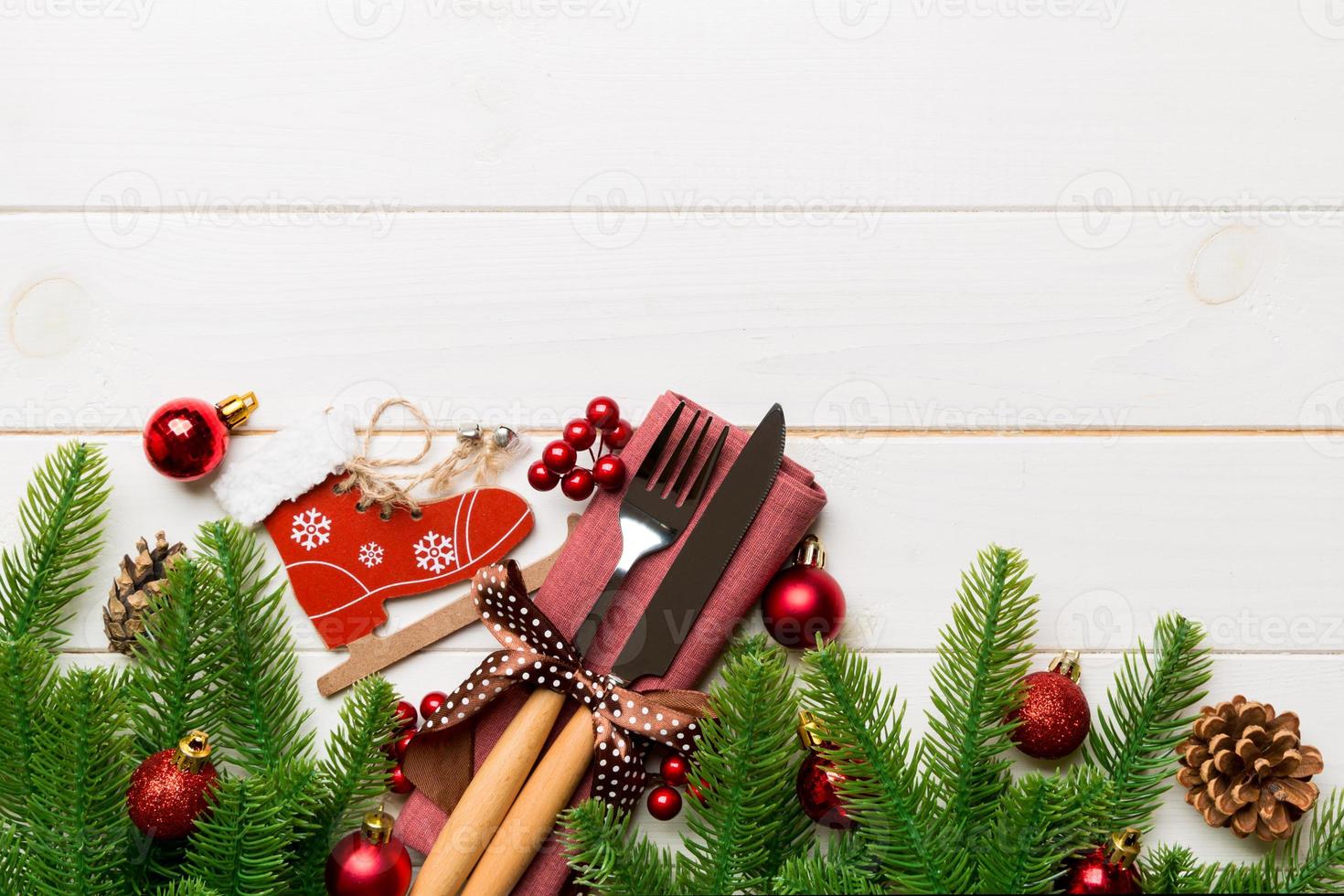 Top view of christmas decorations on wooden background. Fork and knife on napkin tied up with ribbon and empty space for your design. New year pattern concept photo