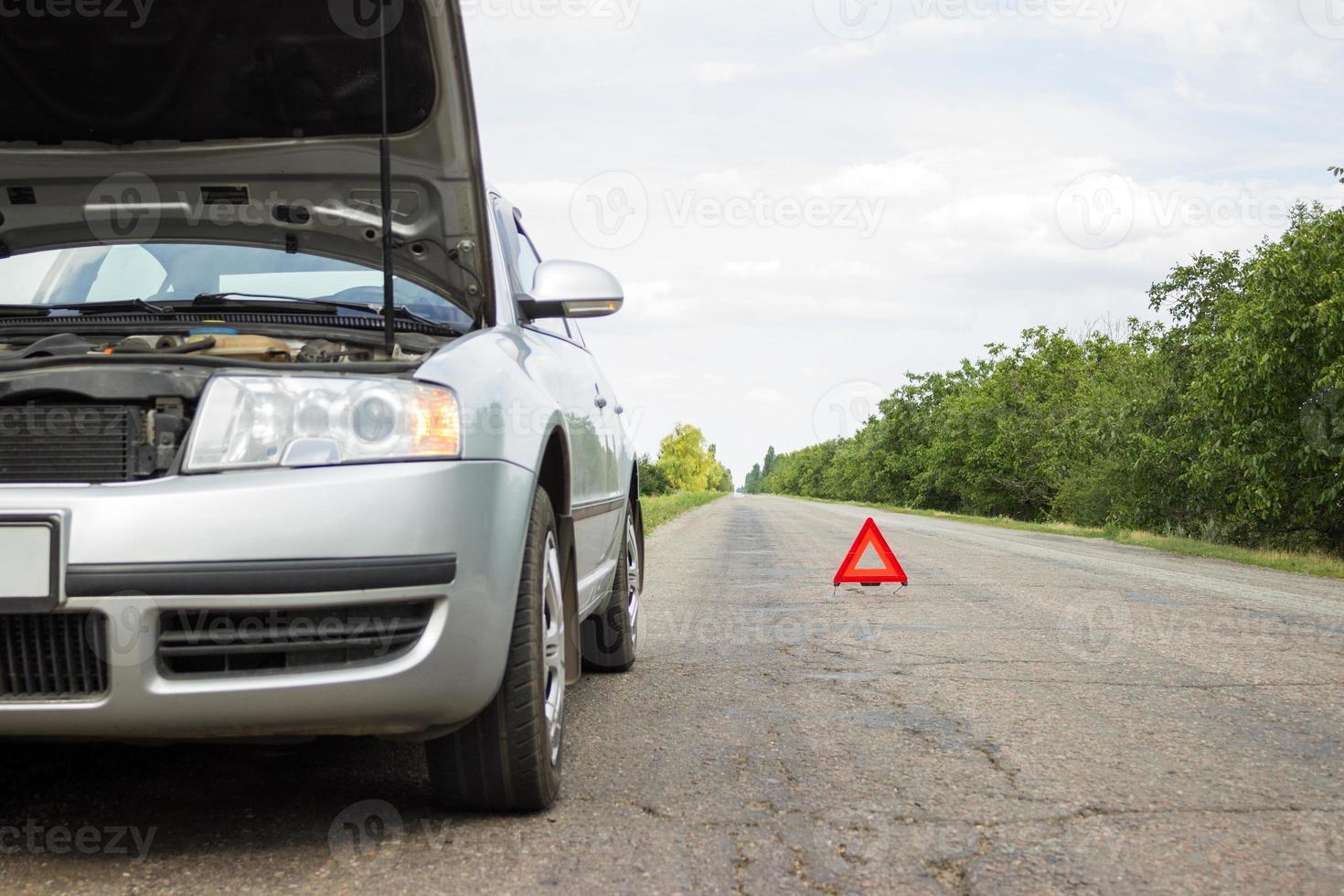 Red triangle of a car on the road. Car warning triangle on the road against the city in the evening. photo