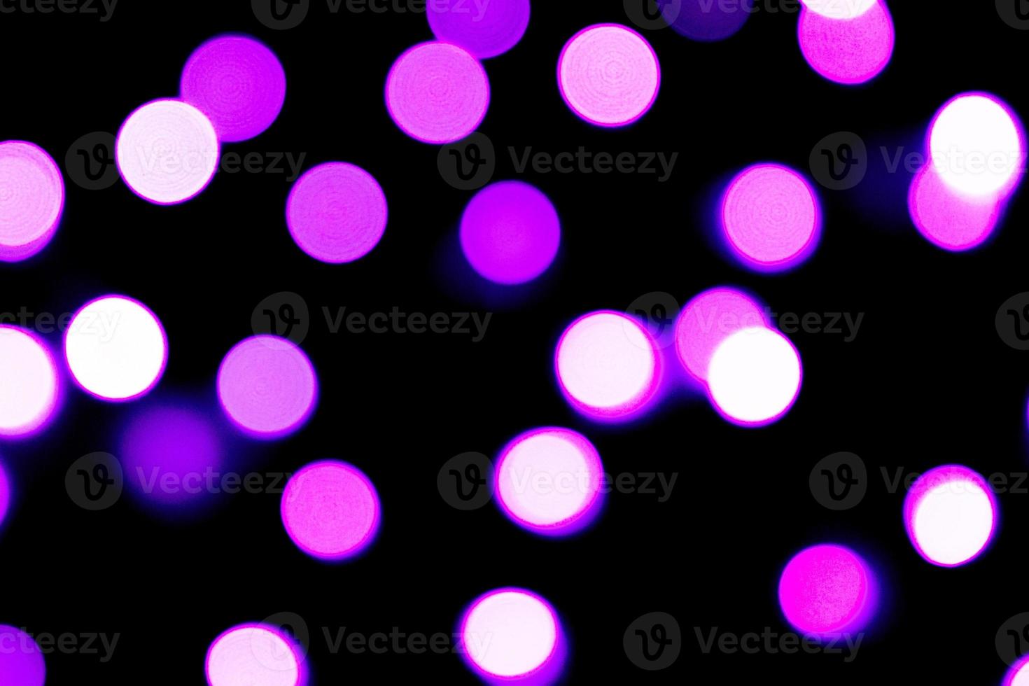 Unfocused abstract purple bokeh on black background. defocused and blurred many round light photo