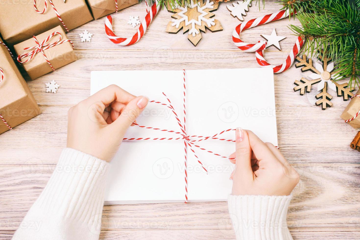 Many envelopes tied with rope. Close-up top view of famale hands with envelope. Pine cones and christmas decoration on old wooden table, desk. Toned photo