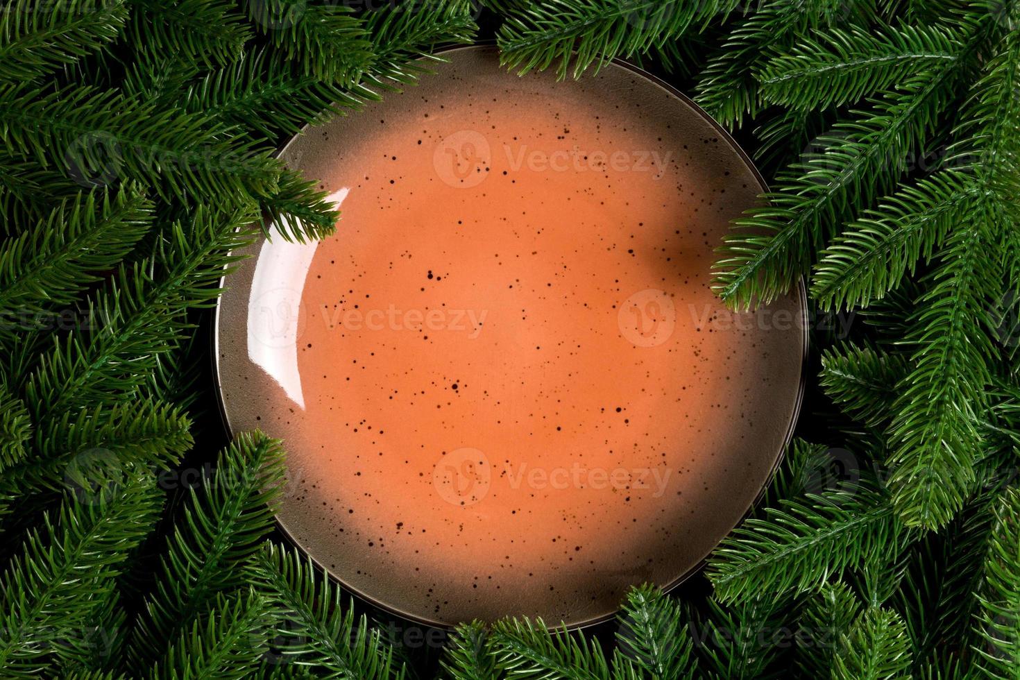 Top view holiday plate among green fir tree branches. Christmas dinner with copy space photo