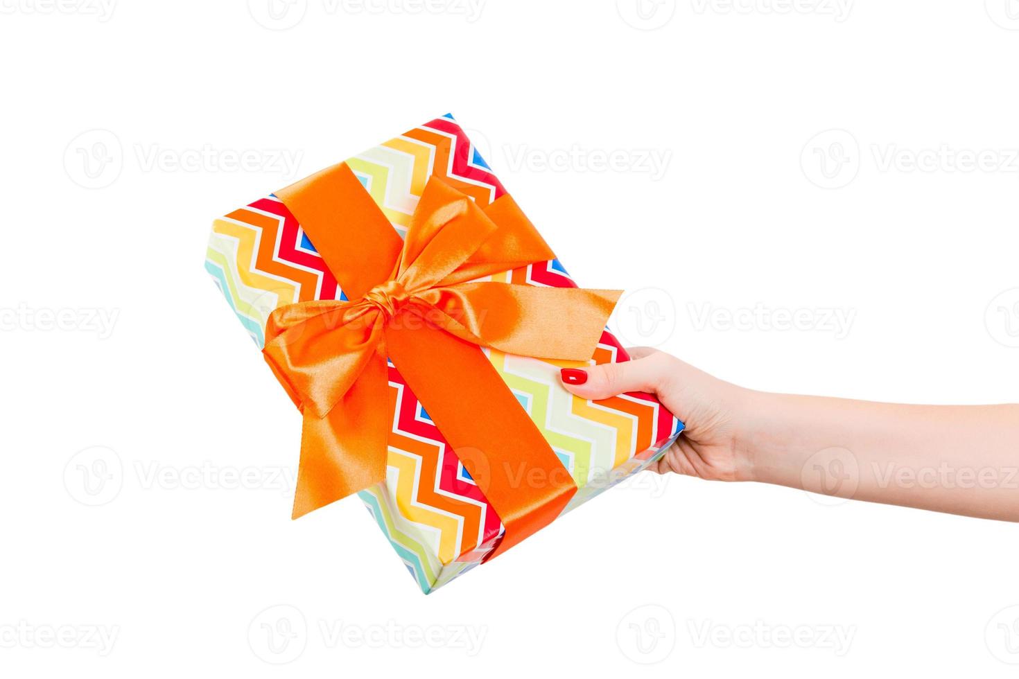 Woman hands give wrapped Christmas or other holiday handmade present in colored paper with orange ribbon. Isolated on white background, top view. thanksgiving Gift box concept photo
