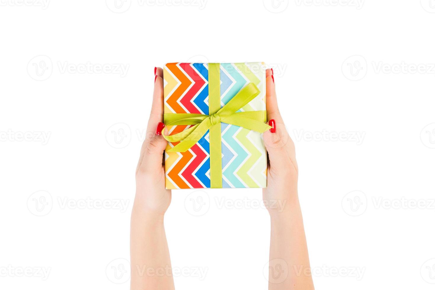 Woman hands give wrapped Christmas or other holiday handmade present in colored paper with green ribbon. Isolated on white background, top view. thanksgiving Gift box concept photo